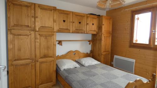 Schlafzimmer mit einem Bett und Holzschränken in der Unterkunft Appartement Yeti Immobilier 2 in Thollon