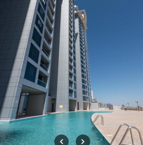 a building with a swimming pool in front of a building at LuxeHome where blue sea & white sands greets you in Ajman