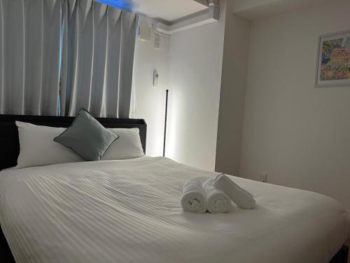 a bedroom with a white bed with towels on it at Coral Gate in Kume コーラルゲートイン久米 in Naha