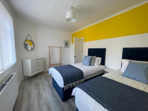 a bedroom with two beds and a yellow wall at Stylish 2-Bed Apartment in Greenock - Sleeps 6 in Greenock
