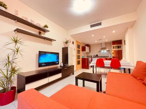 ein Wohnzimmer mit einem orangenen Sofa und einem TV in der Unterkunft Relax LUX apartment on Fenals beach in Lloret de Mar