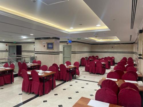 Emaar Taiba Hotel في المدينة المنورة: غرفة طعام مع كراسي حمراء وطاولات في غرفة