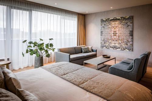 a bedroom with a bed and a couch and a chair at Van der Valk Hotel Enschede in Enschede