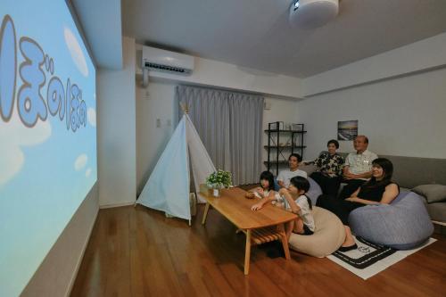 a group of people sitting in a living room at Coral Gate in Kume コーラルゲートイン久米 in Naha