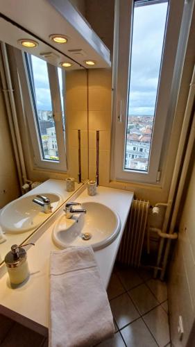 une salle de bain avec deux lavabos et un grand miroir dans l'établissement Travel Homes - Le Wilson, face à la gare, à Mulhouse
