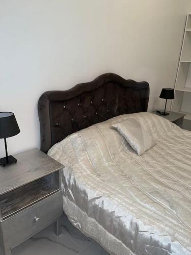 een bed in een slaapkamer met 2 nachtkastjes en een bed met een kussen bij Le Bourget super appartement au centre ville in Le Bourget