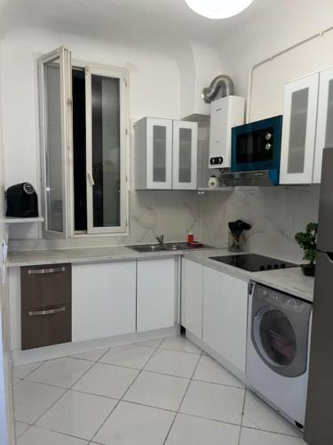 een keuken met witte kasten en een wasmachine bij Le Bourget super appartement au centre ville in Le Bourget