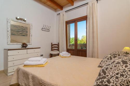 a bedroom with a bed with a dresser and a window at Can Berguins in Búger