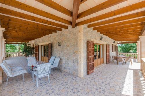 an outdoor patio with chairs and a wooden ceiling at Can Berguins in Búger