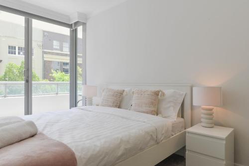 a white bedroom with a bed and a window at Great Location! Darling Harbour Superb 2BR Apt in Sydney