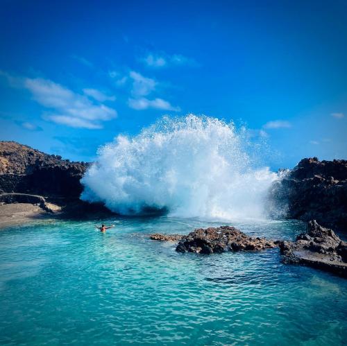 a person riding a large wave in the ocean at Casa Bella Vista frente al mar y piscina natural. in Charco del Palo