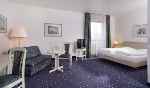 een hotelkamer met een bed en een bank bij Wyndham Garden Duesseldorf Mettmann in Mettmann