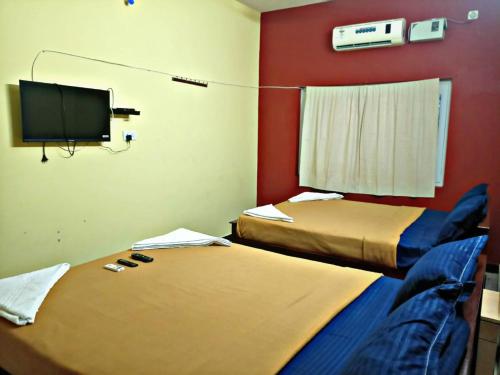 een kamer met 2 bedden en een flatscreen-tv bij Reves by Le Apex in Kottakupam