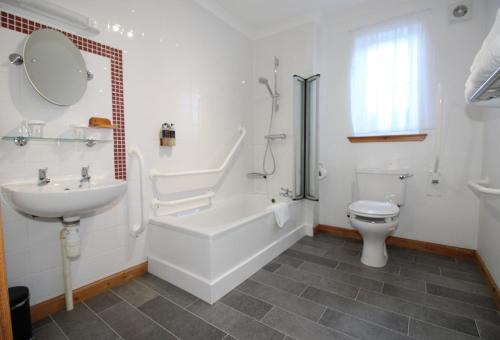 a bathroom with a tub and a sink and a toilet at Temple View Hotel in Carinish