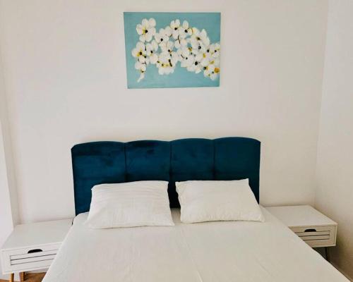 Bett mit blauem Kopfteil und zwei weißen Kissen in der Unterkunft Joy City Stay Mara M10-12 in Timişoara