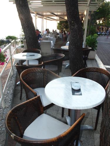 a table and chairs in an outdoor restaurant with trees at Hotel Maritimo in Makarska