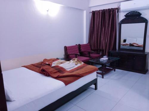 1 dormitorio con cama, espejo y silla en Hotel Khursheed Palace, en Rawalpindi