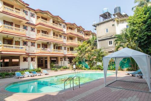 a swimming pool in front of a large building at CherryStay Holiday Resort -Candolim Beach in Candolim