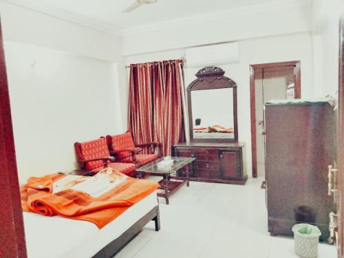 a bedroom with a bed and a chair and a mirror at Hotel Khursheed Palace in Rawalpindi