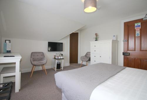 a bedroom with a bed and a desk and a tv at Temple View Hotel in Carinish