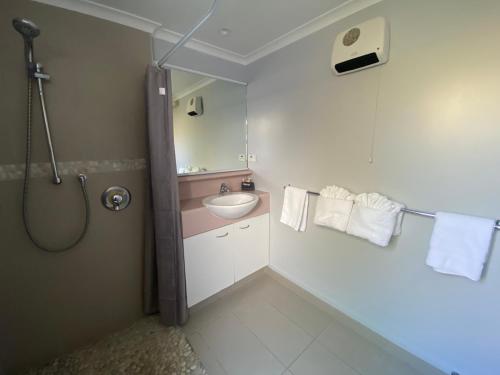 a bathroom with a sink and a shower with towels at Lakeside Taupo Motel in Taupo