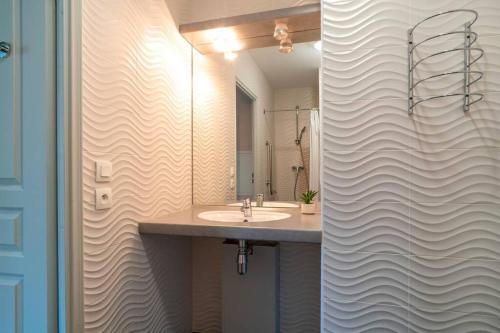 La salle de bains est pourvue d'un lavabo et d'un miroir. dans l'établissement Les Thermes 408 - Appt pour 4 avec piscine partagée, à Concarneau