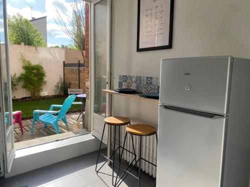 Il comprend une cuisine équipée d'un réfrigérateur, d'une table et de chaises. dans l'établissement Au Cosy Garden, à Reims