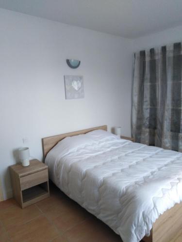 une chambre avec un lit blanc et une table de chevet dans l'établissement Gîte Les Songes, à Canet