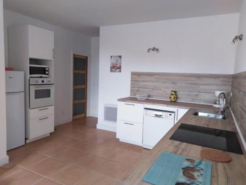 een keuken met witte kasten en een houten aanrecht bij Gîte Les Songes in Canet