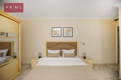 1 dormitorio con 1 cama blanca grande y 2 mesitas de noche en Prime Select Kattameya One, en El Cairo