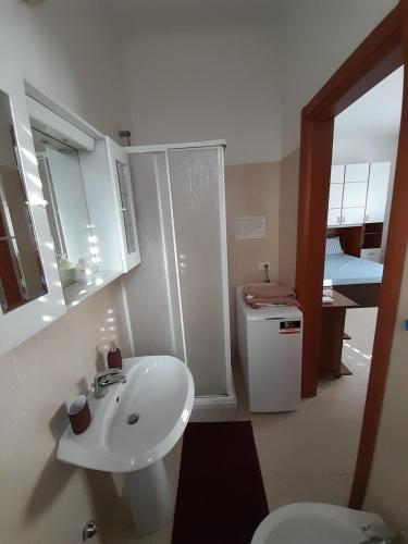 La salle de bains est pourvue d'un lavabo blanc et de toilettes. dans l'établissement Breve Ristoro, à Parme