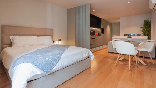 a bedroom with a bed and a table and a kitchen at Casa do Canal do Paraiso in Aveiro