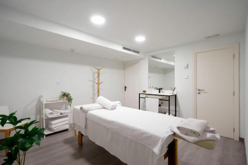 a white bedroom with a bed and a mirror at ILUNION Palmanova Mallorca in Palmanova