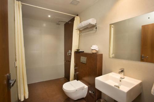 ein Badezimmer mit einem Waschbecken, einem WC und einem Spiegel in der Unterkunft Hotel Keerthi in Thiruvananthapuram