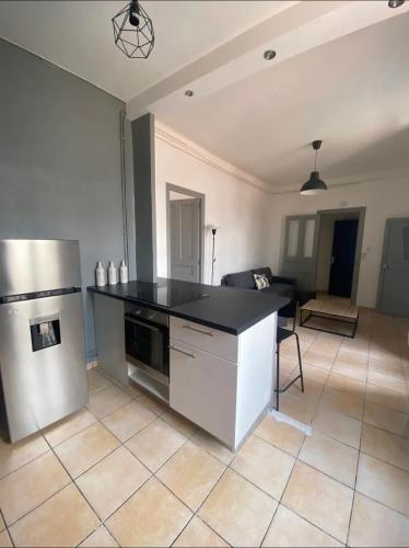 Il comprend une cuisine équipée d'un comptoir noir et d'un réfrigérateur. dans l'établissement Liberté 2 -Spacieux Appartement proche Polygone et centre ville - Beziers - Wifi - Tv Connecté, à Béziers