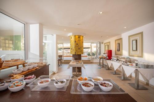 a room with many bowls of food on display at Kitro Beach Hotel - Adults Only in Agios Nikolaos