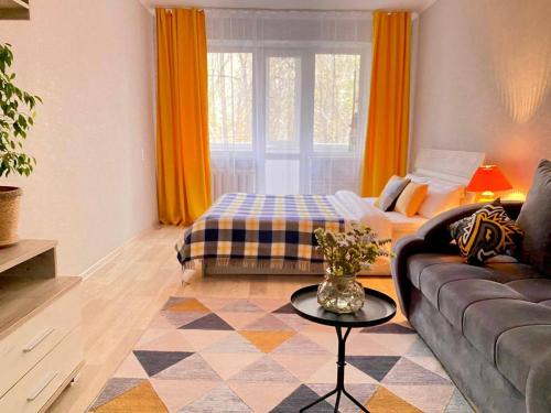 ein Wohnzimmer mit einem Sofa und einem Tisch in der Unterkunft Уютная однушка в центре города in Temirtaū