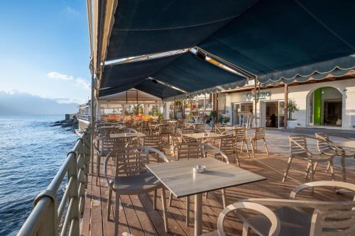 ein Restaurant mit Tischen und Stühlen und dem Meer in der Unterkunft Kitro Beach Hotel - Adults Only in Agios Nikolaos