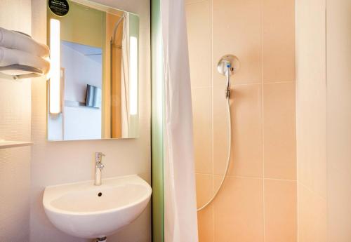 La salle de bains est pourvue d'un lavabo et d'une douche avec un miroir. dans l'établissement B&B HOTEL Nantes Rezé St Sébastien, à Saint-Sébastien-sur-Loire