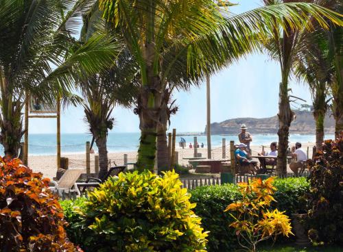 a beach with palm trees and people sitting at a table at Hotel Kundalini in Montañita