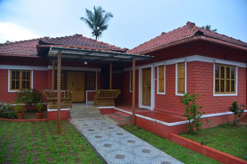 a red house with a palm tree behind it at Panchavati Home Stay in Sringeri