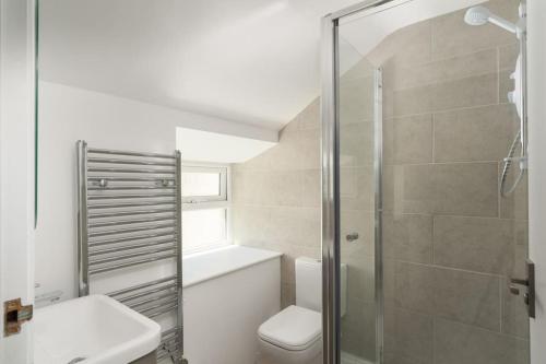 聖賈斯特的住宿－Bright and Modern St Just 1 bedroom apartment in old Cornwall，一间带卫生间和玻璃淋浴间的浴室