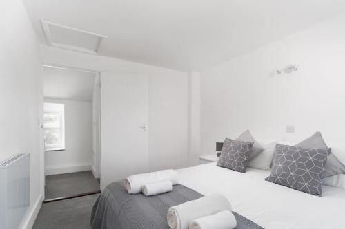 a white bedroom with a bed and a chair at Bright and Modern St Just 1 bedroom apartment in old Cornwall in St Just