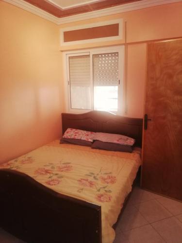 um pequeno quarto com uma cama e uma janela em Appartement Boekidan/Al houceima 