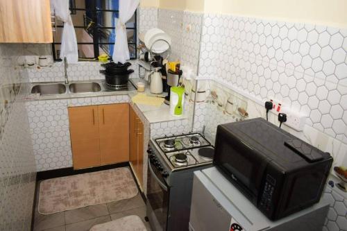 a small kitchen with a stove and a microwave at Crystal Homes Nanyuki Haven 2-BR Gem in Nanyuki