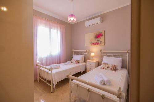 two beds in a small room with a window at Aleli Villas with Tennis Court in Minia