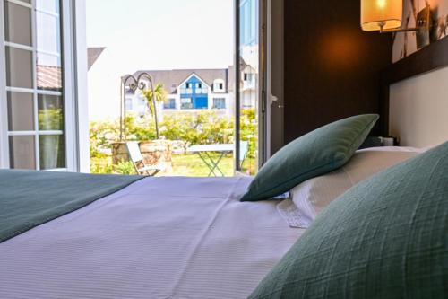 a bed with green pillows in a room with a window at Quality Hotel La Marebaudière Vannes Centre in Vannes