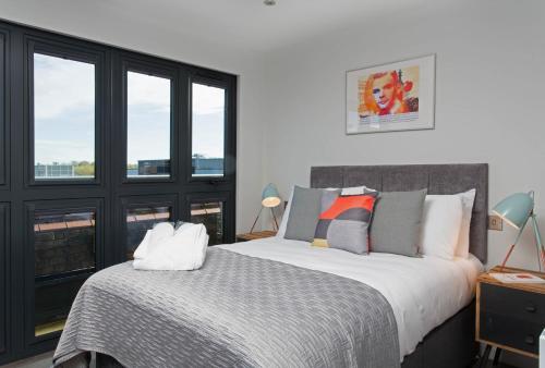 a bedroom with a large bed and windows at Cotels at 7Zero1 Serviced Apartments - Modern Apartments, Superfast Broadband, Free Parking, Centrally Located in Milton Keynes