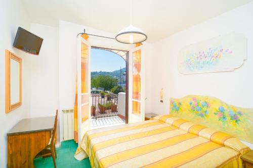 a bedroom with a bed and a desk and a balcony at Hotel Terme Principe in Ischia