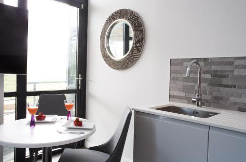 a kitchen with a table and a sink and a mirror at Cotels at 7Zero1 Serviced Apartments - Modern Apartments, Superfast Broadband, Free Parking, Centrally Located in Milton Keynes
